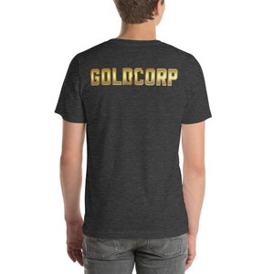 May include: A dark heather grey t-shirt with the text "GOLDCORP" printed in gold on the back.