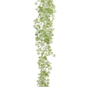 May include: A long, artificial green vine with small white flowers hanging down. The vine is perfect for adding a touch of greenery to any space.