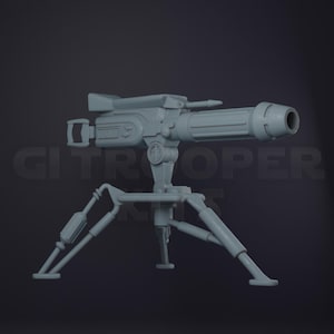 May include: A light gray, unpainted miniature model of a sci-fi heavy blaster cannon mounted on a tripod stand. The weapon features a cylindrical barrel, a rectangular receiver, and a rear handle. The tripod has three articulated legs.