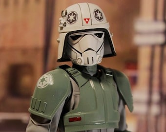 May include: A green and gray action figure of a Star Wars Stormtrooper wearing a helmet with a white symbol. The figure is standing on a light gray surface.