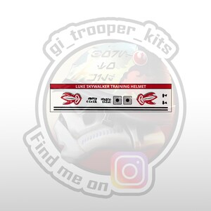 May include: A red and white sticker with the text "LUKE SKYWALKER TRAINING HELMET" and a red and white graphic of a lightsaber. The sticker is on a white background.