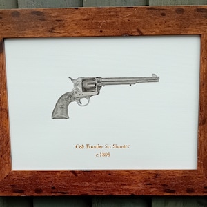 Op de afbeelding: Een ingelijste zwart-witte tekening van een Colt Frontier Six Shooter revolver, met de tekst "Colt Frontier Six Shooter c.1898" onder de afbeelding.