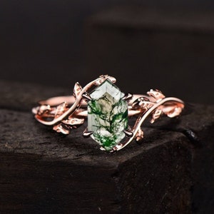 May include: A rose gold ring with a green moss agate gemstone set in a leafy design.