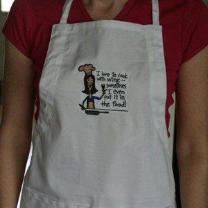 May include: White apron with a pocket and the embroidered phrase "I love to cook with wine - sometimes I even put it in the food!" A cartoon woman with a chef's hat is holding a wine glass and a pan.