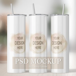 May include: Three white 20oz skinny tumblers with clear straws. Each tumbler has a gold circle with the text "YOUR DESIGN HERE" on a white background. The text "PSD MOCKUP" is below the tumblers, with the text "20oz Skinny Tumbler" below that.