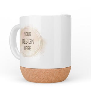 May include: White ceramic mug with a cork base. The mug has a gold circle with the text "YOUR DESIGN HERE" in the centre.