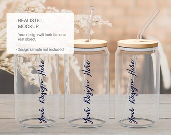 May include: Three clear glass can-shaped tumblers with bamboo lids and glass straws. Each tumbler has the text "Your Design Here" in a dark blue script. The image includes the text "REALISTIC MOCKUP" and "Your design will look like on a real object."