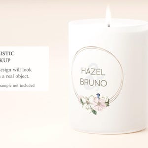 May include: A white pillar candle with a lit wick. The candle features a circular design with the names "HAZEL & BRUNO" and floral accents. Text on a card reads "REALISTIC MOCKUP. Your design will look like on a real object. *Design sample not included."