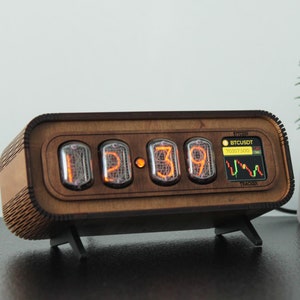 May include: A wooden clock with a digital display showing the time 1:39. The clock also displays a graph with the text "BTCCUSDT 70351.500" and "TRACKER".