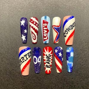 May include: A set of ten long, coffin-shaped false nails. Each nail features a unique design, including stars, paisley, the Levi's logo, and the word "COWBOY". The nails are painted in red, white, blue, and pink.