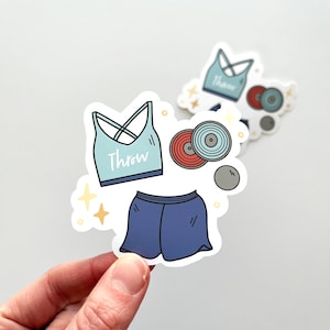 Op de afbeelding: Een verzameling stickers met sportuitrusting en -kleding. De stickers tonen een lichtblauwe sport-bh met het woord "Throw", een blauwe short, een discus en een kogel. De stickers hebben witte randen en een cartoonstijl.