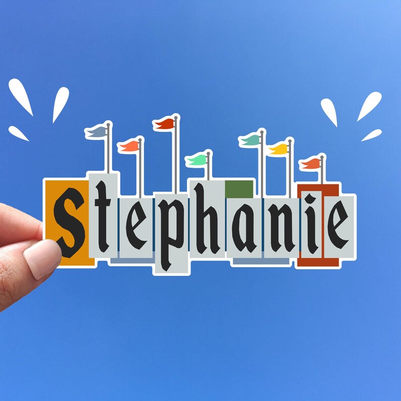 Pode incluir: Um adesivo com o nome "Stephanie" escrito em letras pretas sobre um fundo branco. Cada letra &eacute; cercada por uma borda cinza e tem uma pequena bandeira no topo. As bandeiras s&atilde;o vermelhas, laranja, amarelas, verdes, azuis e roxas.