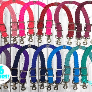 May include: A set of 26 braided leather halter straps with silver buckles and clips. The straps are available in a variety of colours, including pink, purple, blue, and green. The straps are shown against a white wood background.