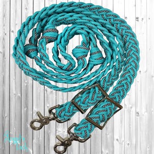 May include: Turquoise braided rope with silver-coloured hardware. The rope has a black and white pattern woven into the turquoise. The hardware includes two rectangular buckles and two swivel snap hooks.