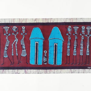 May include: A batik wall hanging with a red background featuring a row of women in black and white carrying pots on their heads. Two blue houses with black doors and windows are in the center of the image. The text "ARAUTO" is in the bottom right corner.