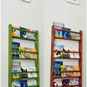 May include: Two wooden bookshelves with different colored stains, one green and one brown. Both shelves are filled with children's books with colorful covers. The shelves are labeled with the name "Olivia" at the top.