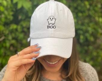 Op de afbeelding: Witte baseballpet met een zwart geborduurd spook en het woord "BOO" op de voorkant.