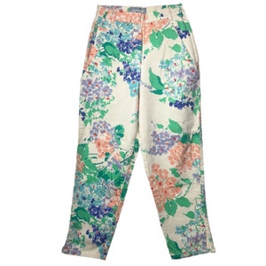 May include: White pants with a floral print featuring pink, blue, and green flowers. The pants have a high waist and a straight leg.
