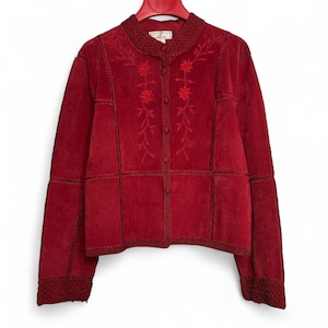 May include: A red suede jacket with floral embroidery and a button-up front. The jacket features a round collar and is displayed on a red hanger. The sleeves and body are constructed from panels, with decorative stitching. The jacket is a deep shade of red.