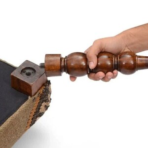 May include: A wooden chair leg with a threaded end is being screwed into a square wooden block attached to the chair's base. The chair is upholstered in a brown and beige fabric.
