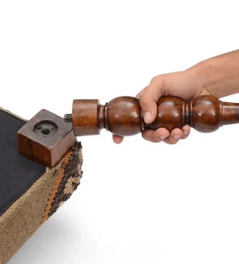 May include: A wooden chair leg with a threaded end is being screwed into a square wooden block attached to the chair's base. The chair is upholstered in a brown and beige fabric.