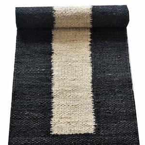 May include: Black and white striped jute rug with a long, narrow design. The rug is made of natural fibers and has a rough texture.