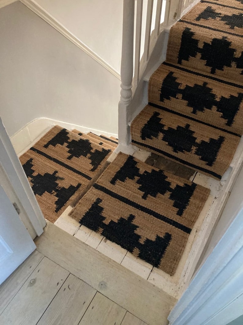 May include: A set of black and tan patterned stair treads. The treads are made of a woven material and have a geometric design.