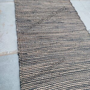 May include: A black and natural jute rug with a woven pattern. The rug has a textured surface and is made of natural fibres.