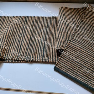 May include: Two striped jute rugs in black and beige. The rugs are woven with a simple pattern and have a natural, rustic look.