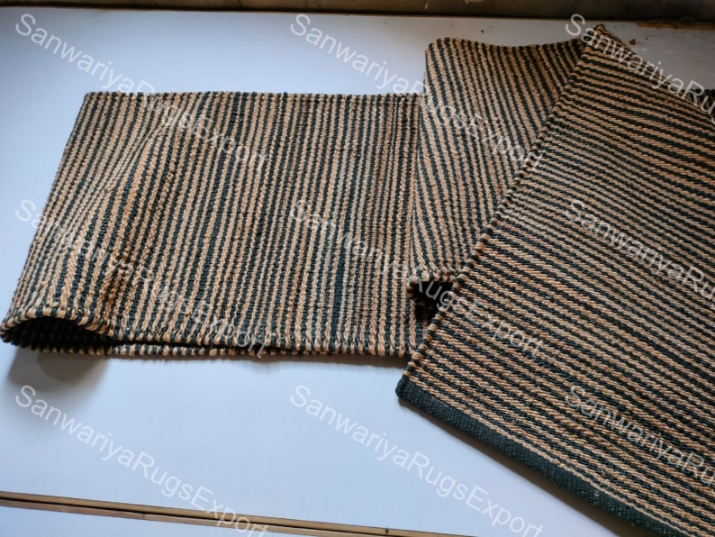 May include: Two striped jute rugs in black and beige. The rugs are woven with a simple pattern and have a natural, rustic look.