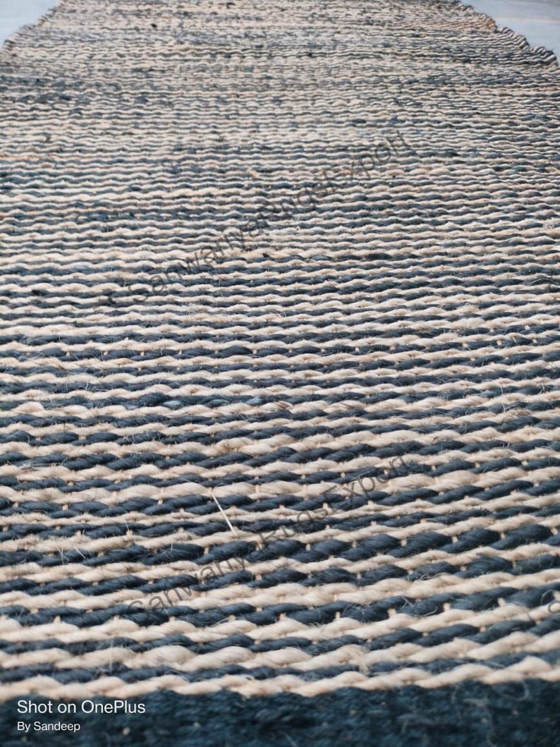 May include: A black and natural jute rug with a woven striped pattern. The rug is made of natural fibres and has a rustic look.