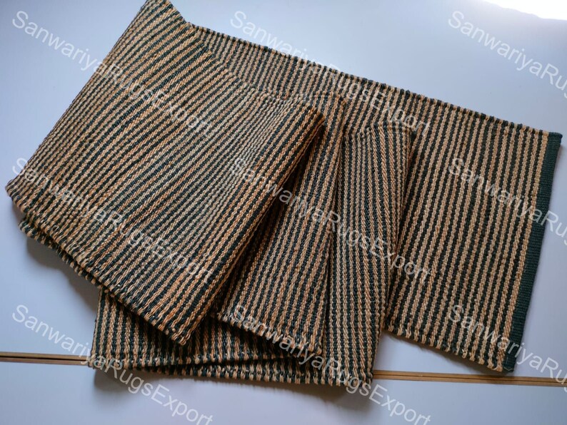 May include: Four striped woven mats in shades of brown and green. The mats are made of natural fibres and have a rustic look.