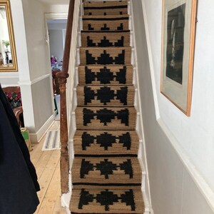 May include: A set of stair treads with a black and tan geometric pattern. The treads are made of a natural fibre material, such as jute or sisal.