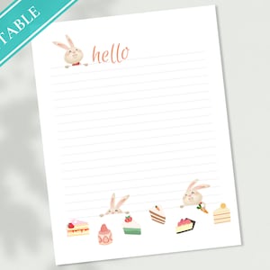 Puede incluir: Papel con líneas imprimibles con un conejo mirando por encima y la palabra "hello" escrita en naranja. La parte inferior de la página tiene un borde de conejos y rebanadas de pastel.