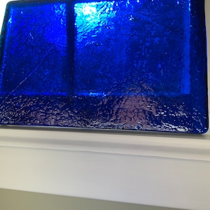 May include: A rectangular blue glass tray with a textured surface. The tray is made of thick glass and has a deep blue color.