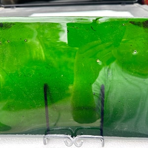 May include: A rectangular green glass tray with a textured surface. The tray is sitting on a white surface.