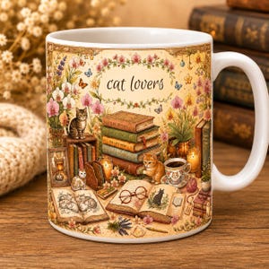 Può includere: Una tazza in ceramica bianca con un'illustrazione dettagliata di gatti, pile di libri, fiori e farfalle. Il testo "cat lovers" è stampato al centro. Il design include una tazzina da tè, occhiali e candele, il tutto in caldi colori vintage.