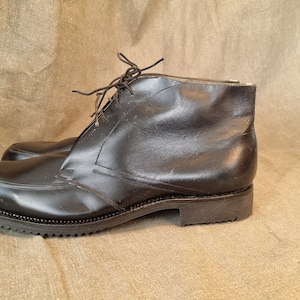 May include: Black leather ankle boots with laces. The boots have a rounded toe and a thick sole.