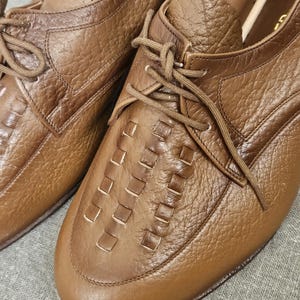 May include: A pair of brown leather lace-up shoes with a woven pattern on the toe. The shoes have a classic design and are made of high-quality leather.