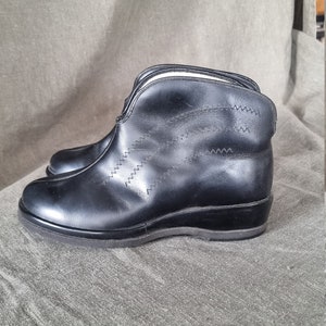 Peut inclure: Bottines en cuir noir avec une fermeture éclair sur le côté et un motif de couture décoratif. Les bottes ont un talon bas.