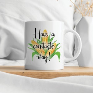 May include: White ceramic mug with a black and white graphic of corn on the cob and the text "Have a corn-tastic day!"