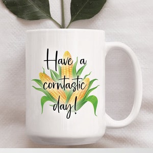 May include: White ceramic coffee mug with a black and green corn design and the text "Have a corntastic day!"