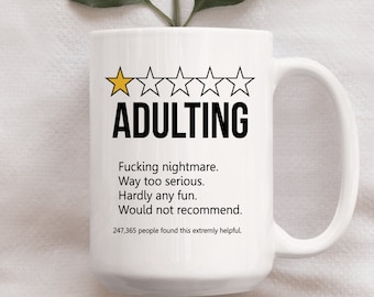 May include: White coffee mug with a one-star rating and the text "ADULTING" in black. The text below reads "Fucking nightmare. Way too serious. Hardly any fun. Would not recommend. 247,365 people found this extremely helpful."