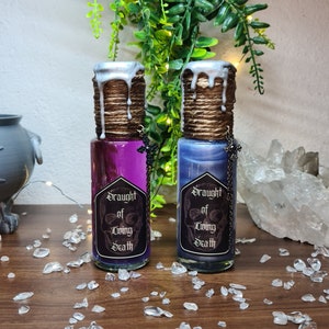 May include: Two small glass bottles with silver lids and a brown twine wrap. The bottles contain a purple and a blue liquid. Each bottle has a black and white label that reads "Draught of Living Death".