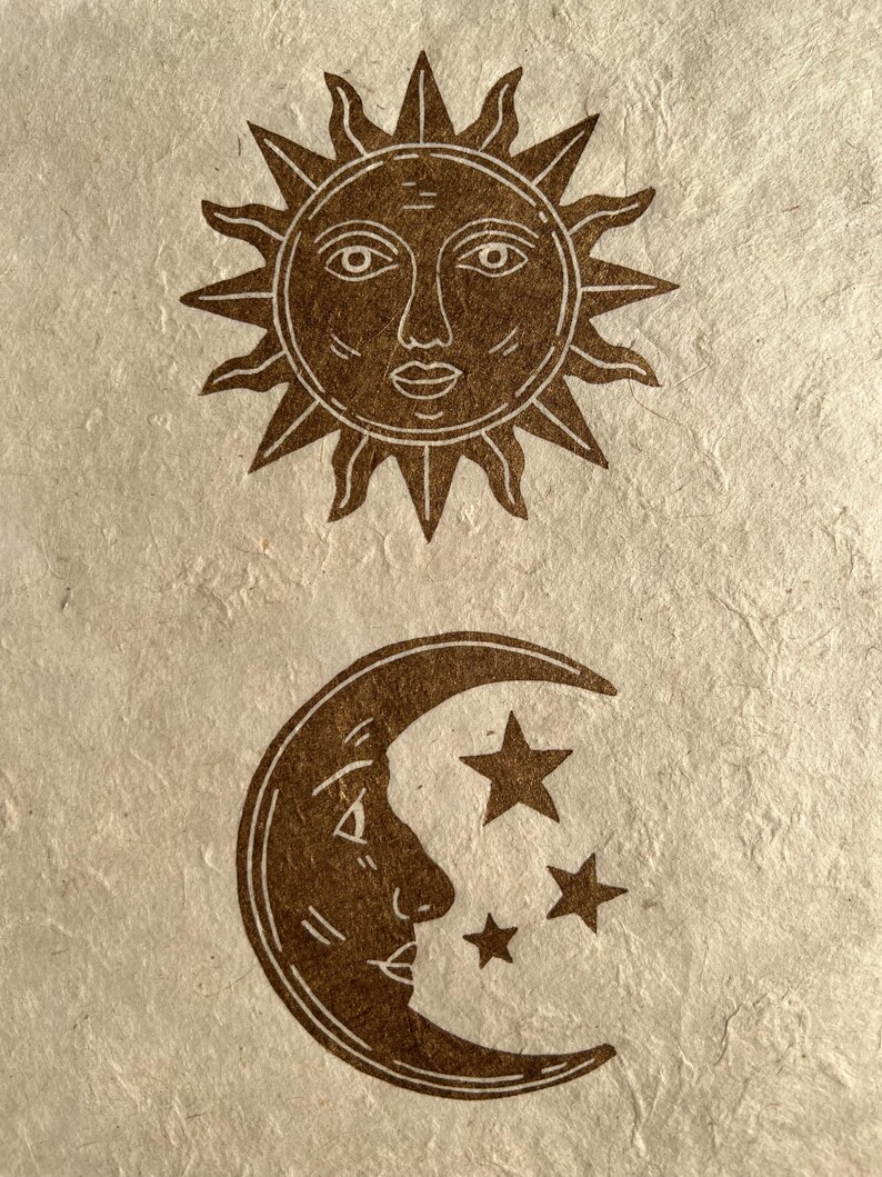 May include: Brown illustration of the sun with a face and radiating lines above a crescent moon with a face and three stars. The celestial bodies are on a textured, off-white background.