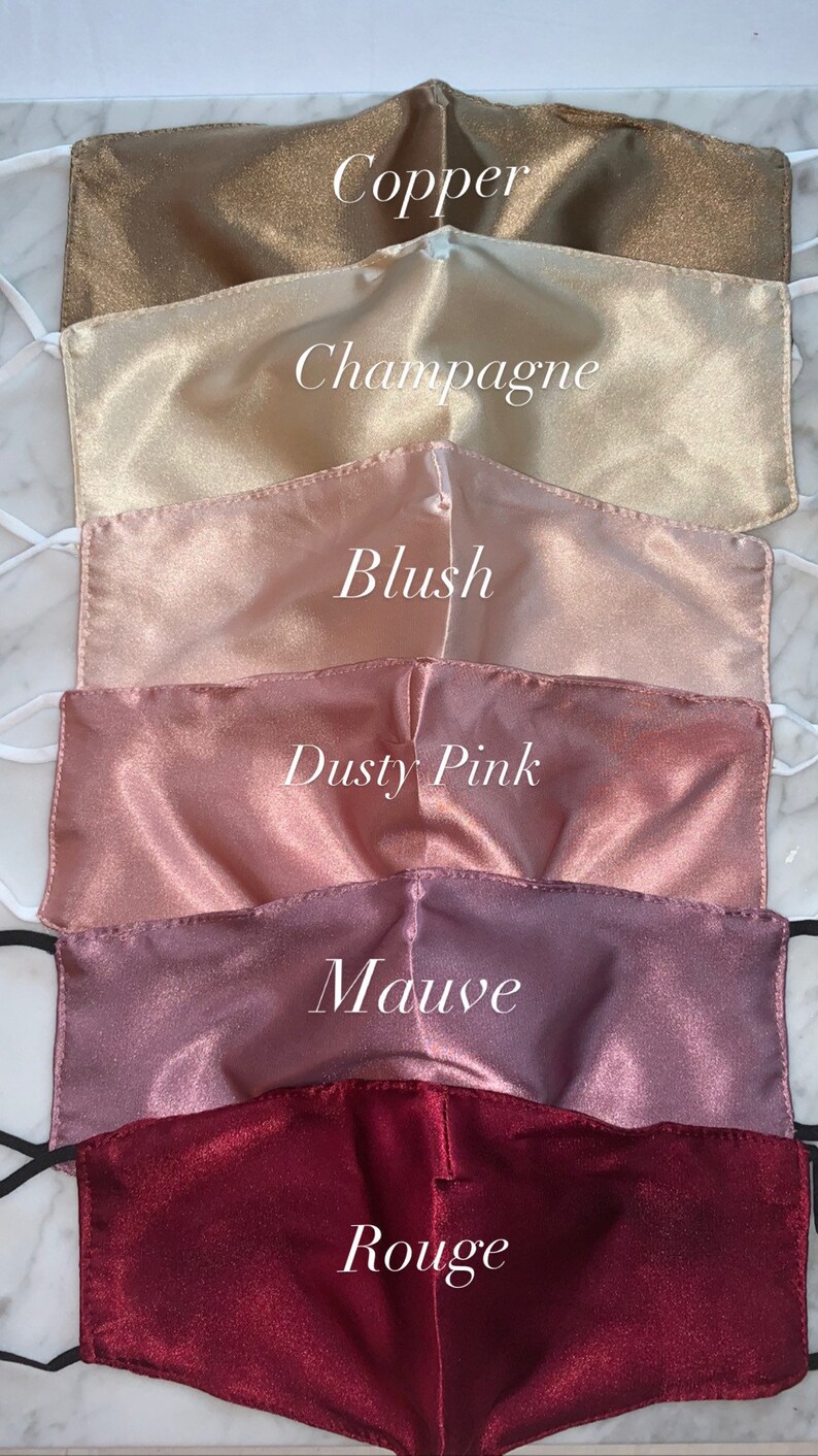May include: Six satin face masks in different shades of pink and brown. The masks are labeled with the colors: Copper, Champagne, Blush, Dusty Pink, Mauve, and Rouge.