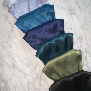 May include: Seven satin fabric face masks in various colors, including light gray, teal, navy blue, dark green, olive green, and black.