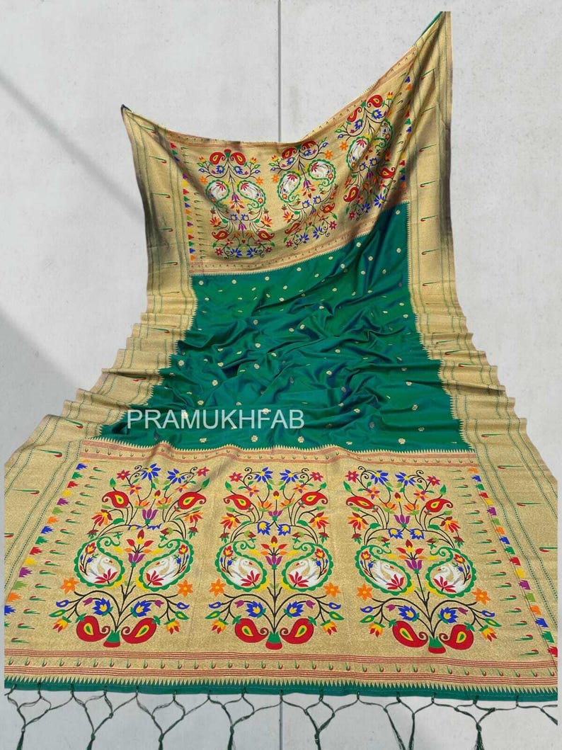 May include: A green and gold saree with intricate floral and paisley embroidery. The saree features a vibrant design with red, blue, yellow, and white accents. The text "PRAMUKHFAB" is visible on the saree.