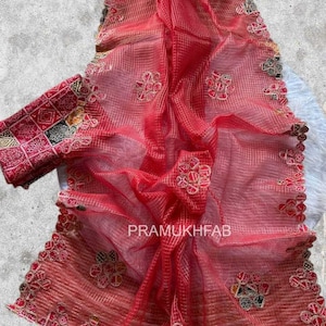 May include: A white ceramic mug with a black handle and the text "But First, Coffee" in a bold, black font. The mug is set against a blurred background, suggesting a cosy setting.