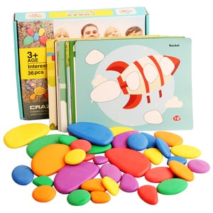 May include: A set of 36 colorful smooth stones for kids to use with picture cards. The cards feature images of a rocket, clouds, and other objects. The stones are a fun and engaging way for children to learn about colors and shapes.